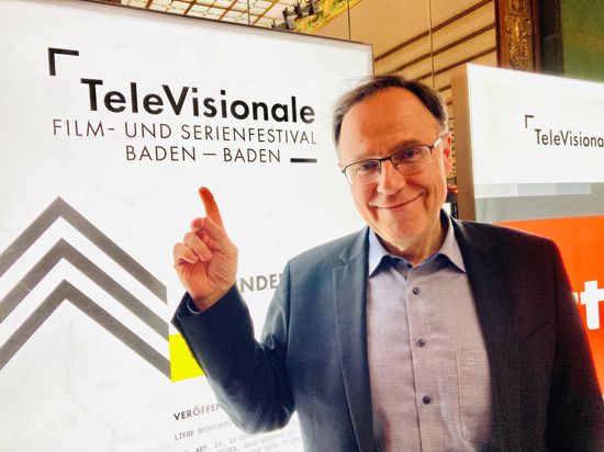 Carl Bergengruen steht vor einem Leuchtdisplay mit der Aufschrift „TeleVisionale“ im Kurhaus in Baden-Baden. 