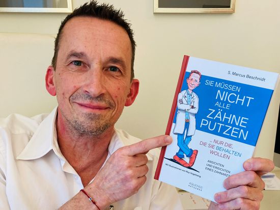 Zahnarzt Marcus Beschnidt aus Baden-Baden hält sein Buch mit dem Titel „Sie müssen nicht alle Zähne putzen, nur die, die sie behalten wollen“ in der Hand. 
