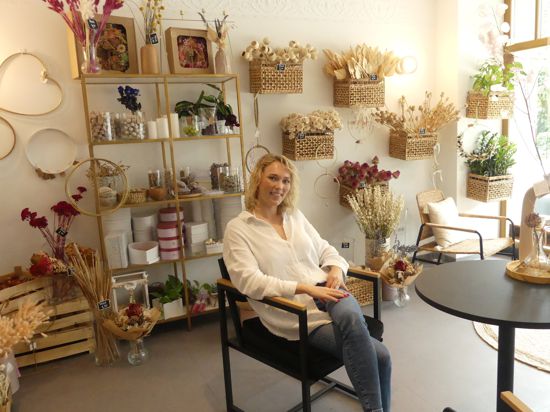 Xenia Karpov sitzt in ihrem Laden mit Trockenblumen im Hintergrund.