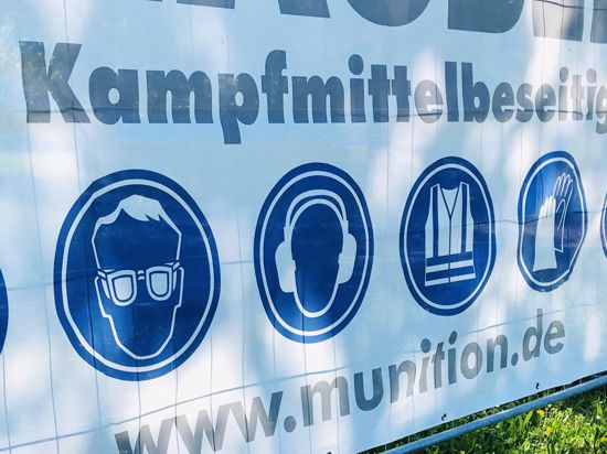 Ein Transparent mit der Aufschrift „Der Kampfmittelbeseitiger“ hängt an einem Zaun im Wörthböschelpark in Baden-Baden.