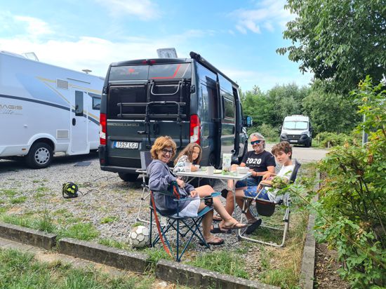 Familie sitzt vor Camper-Bus