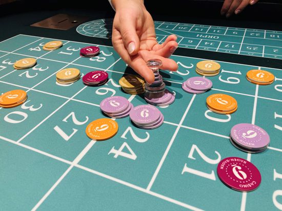 Eine Hand ordnet Chips an einem Roulette-Tisch im Casino Baden-Baden. 
