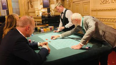 Ein Croupier agiert vor Spielern an einem Spieltisch im Casino Baden-Baden