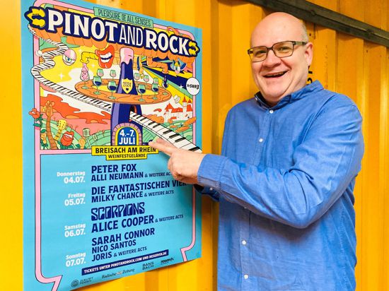 Rantastic-Chef Jens Dietrich steht vor einem Plakat für das Festival Pinot and Rock vom 4. bis 7. Juli in Breisach. 