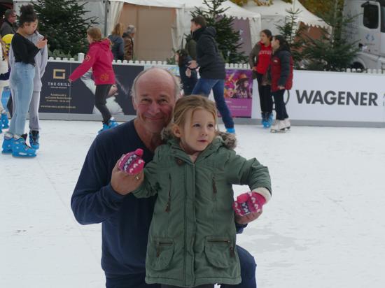 Ein Mann und ein Mädchen stehen auf einer Eisbahn.