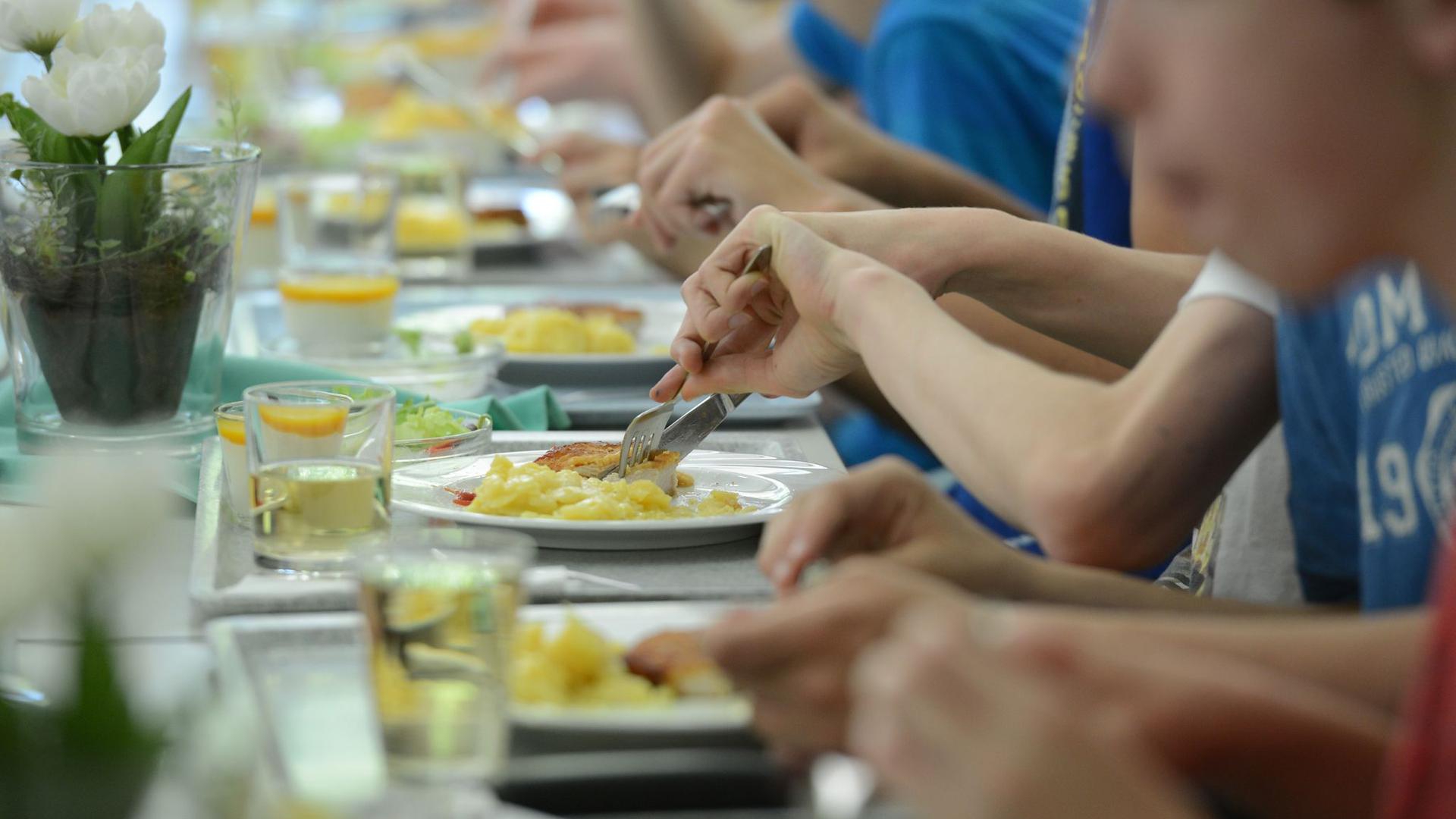 Schüler einer Ganztagsschule essen zusammen in der Mensa.