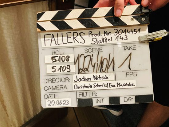 Eine Hand hält eine Klappe für Aufnahmen zur TV-Serie „Die Fallers“. 