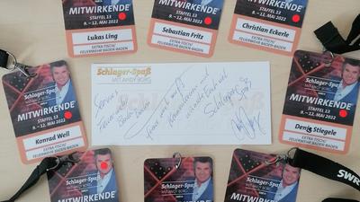 Baden-Badener Feuerwehrmänner haben ihren Pass für eine TV-Aufzeichnung um eine von Schlagerstar und TV-Moderator Andy Borg signierte Botschaft gruppiert. 