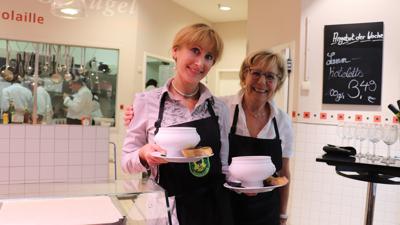 Maria Leuthardt und Marita Versemann-Kessler stehen mit Suppenschüsseln vor der Fischtheke in der Wagener-Markthalle 