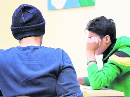 Zwei jugendliche Flüchtlinge sitzen an einem Tisch.