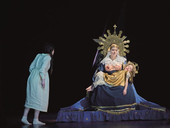 Ein Mädchen (Vivien Hartert) starrt auf eine Muttergottesfiggur mit zerbissener Brust in einer Szene aus der Oper „Die Frau ohne Schatten“ bei den Osterfestspielen 2023 in Baden-Baden in der Regie von Lydia Steier.