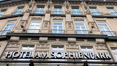 An einer Hausfassade hängt ein Schild mit der Aufschrift „Hotel am Sophienpark“.