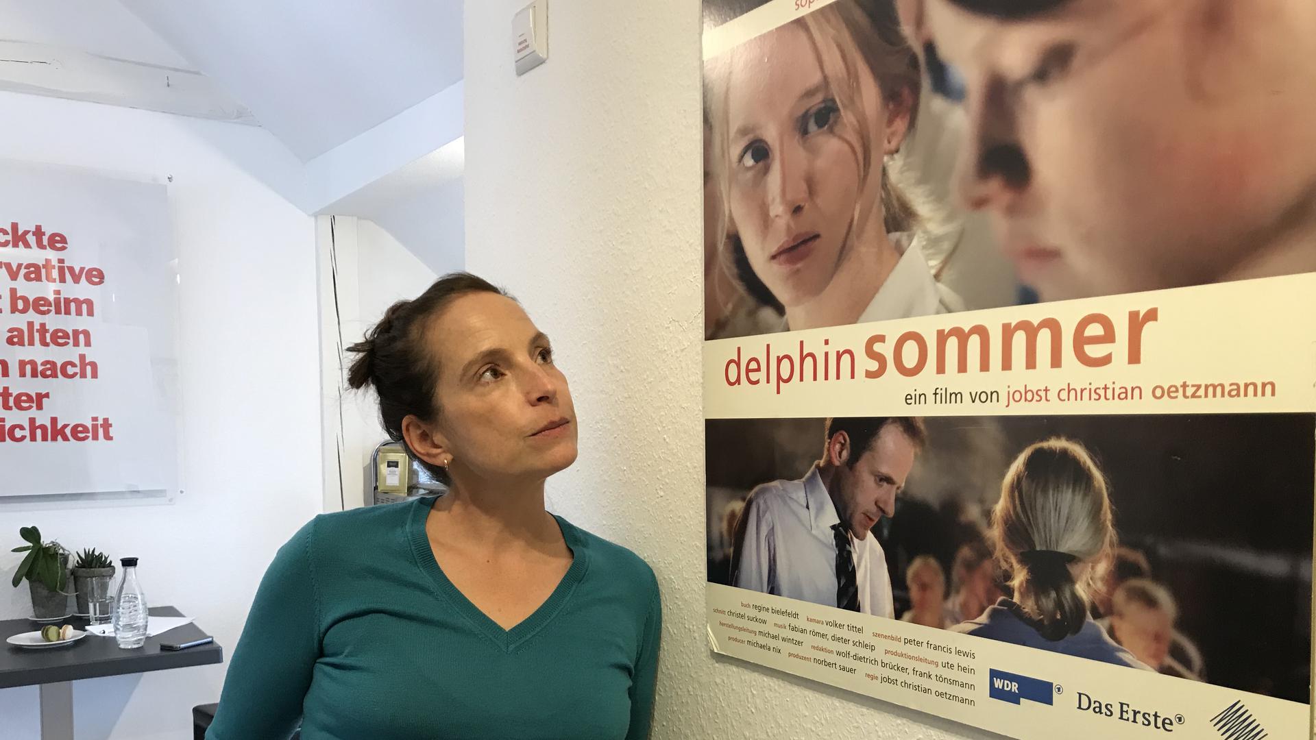 Die Drehbuchautorin Regine Bielefeldt aus Baden-Baden steht vor einem Filmplakat von Delphinsommer.