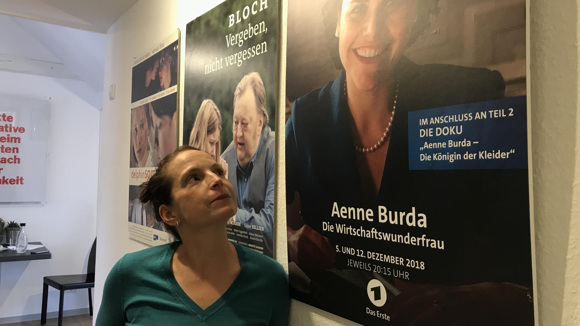 Die Drehbuchautorin Regine Bielefeldt aus Baden-Baden steht vor einem Plakat der ARD-Dokumentation „Aenne Burda - Die Königin der Kleider“ .