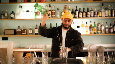 Ein Mann steht hinter einer Bar in Baden-Baden und mixt einen Cocktail.