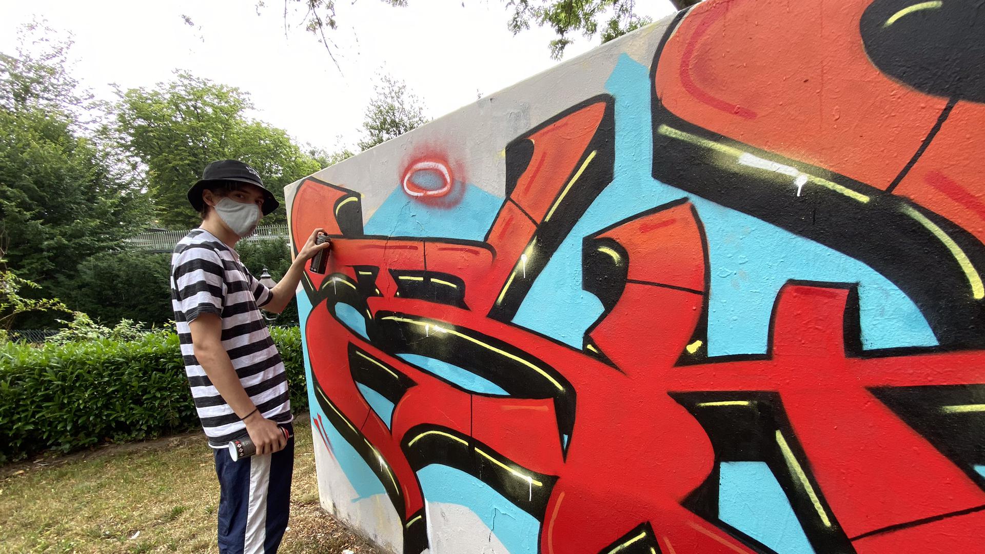 Ein Jugendlicher sprayt mit Graffiti.