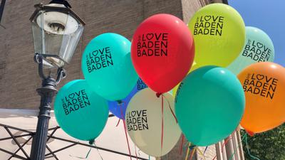 Vor der Trinkhalle in Baden-Baden schweben Luftballons mit der Aufschrift „We love Baden-Baden“.