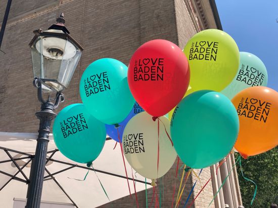 Vor der Trinkhalle in Baden-Baden schweben Luftballons mit der Aufschrift „We love Baden-Baden“.
