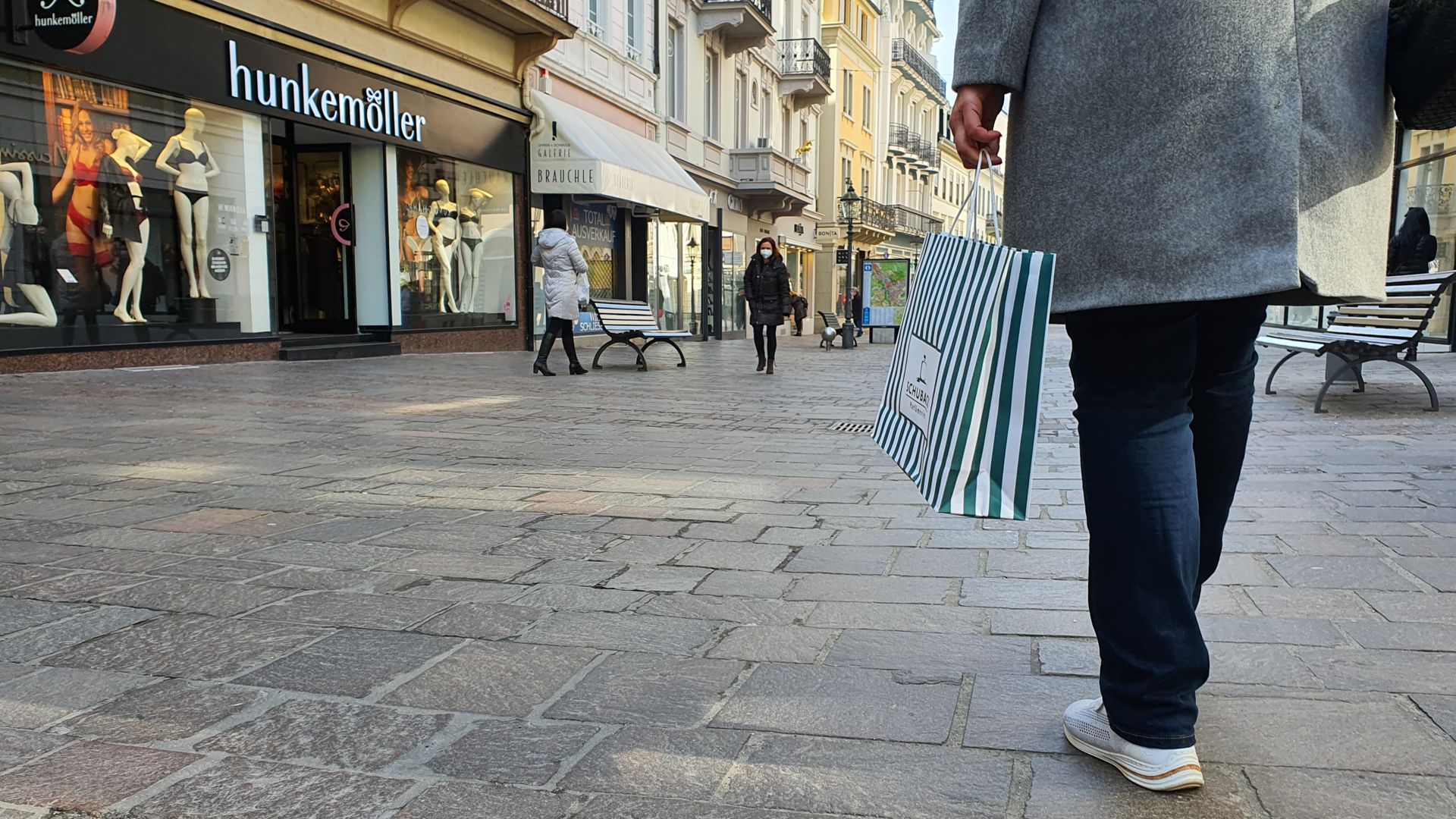 Eine Frau schlendert mit einer Einkaufstüte durch Baden-Baden. 
