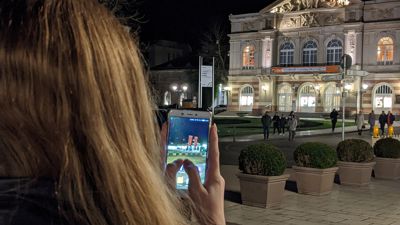 Gut versorgt: Wie diese junge Frau vor dem Theater Baden-Baden profitieren auch die anderen Kunden der drei führenden deutschen Netzbetreiber von einem bereits gut ausgebauten Mobilfunknetz in Baden-Baden. Und es soll durch die Erweiterung um 5G noch besser und schneller werden.