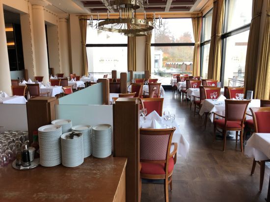 Weiß eingedeckte Tische und rote Polsterstühle stehen im Kurhaus-Restaurant.