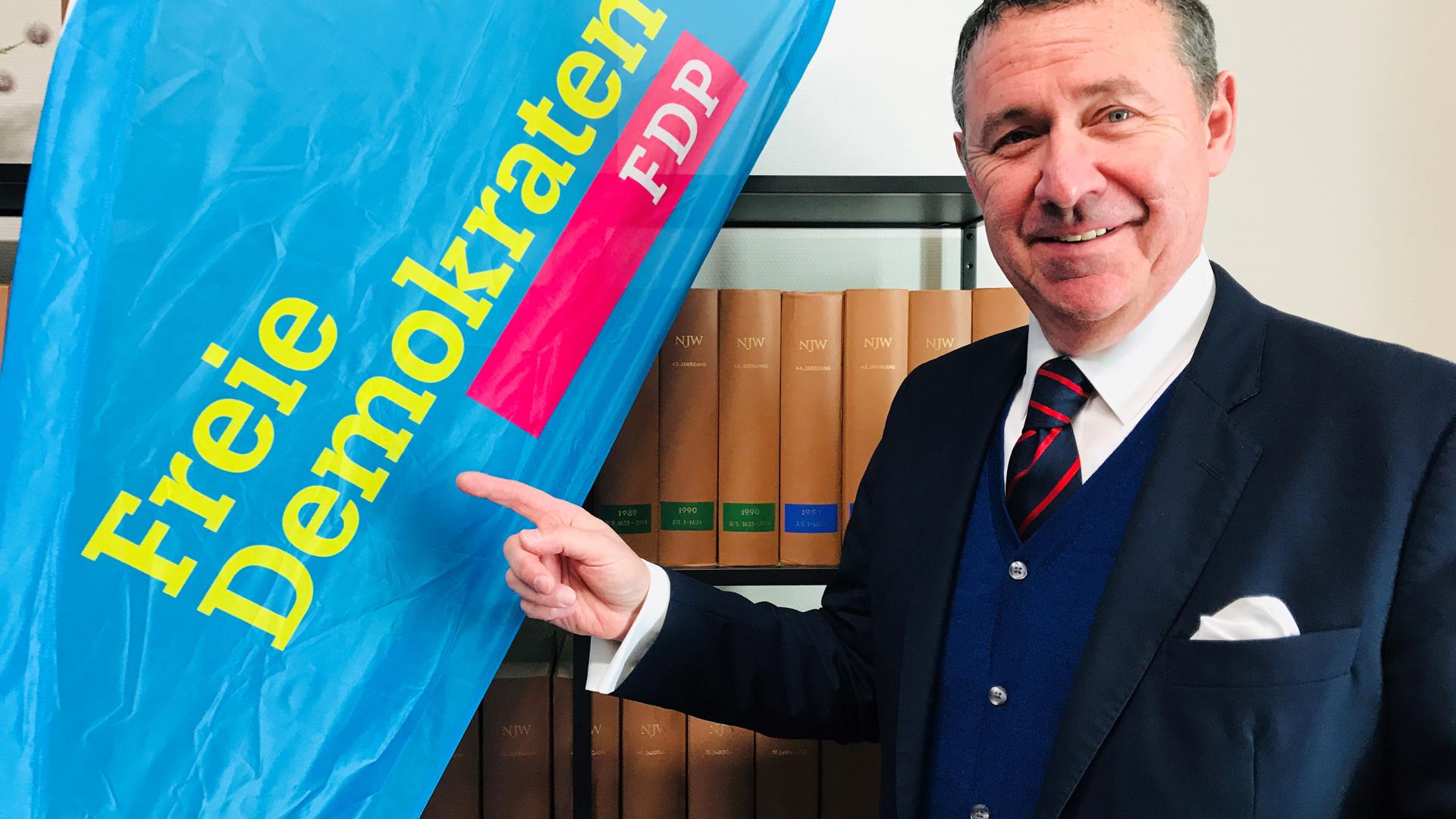 Der FDP-Bewerber für die Landtagswahl im Wahlkreis Baden-Baden, René Lohs, steht vor einem Banner seiner Partei.