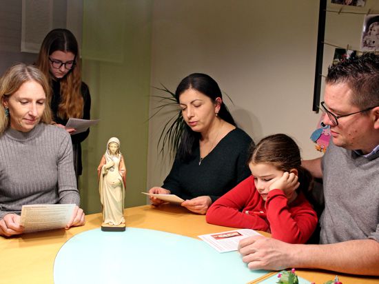 Familien am Tisch mit einer Holzfigur der schwangeren Maria