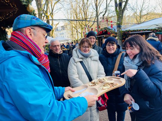 Teilnehmer der geführten Tour über den Weihnachtsmarkt in Baden-Baden probieren Baumkuchen. 