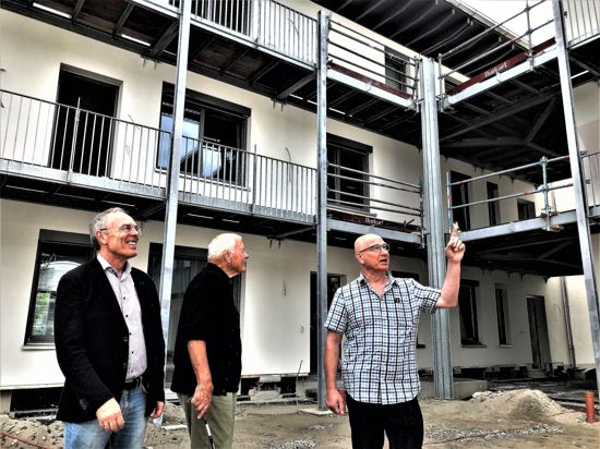 Drei Männer stehen vor einem Neubau.