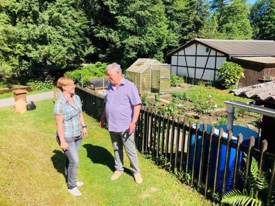 Nicole Siegele und Roland Walter vom Verein Ooswinkelgemeinschaft stehen vor einem Garten der Siedlung in Baden-Baden.