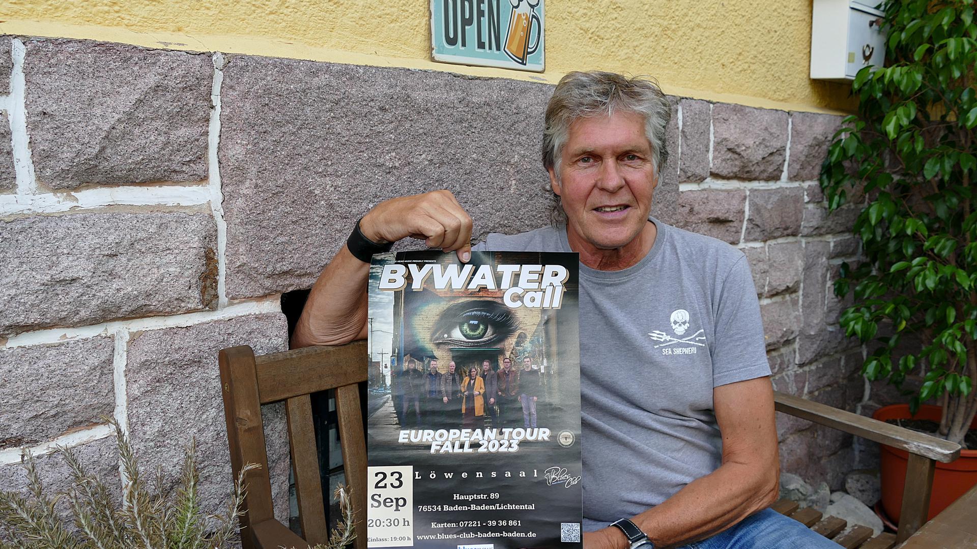 Der Vorsitzende des Bluesclubs, Klaus Hartmann, zeigt ein Plakat von Bywater Call, die den Saisonauftakt gestalten.