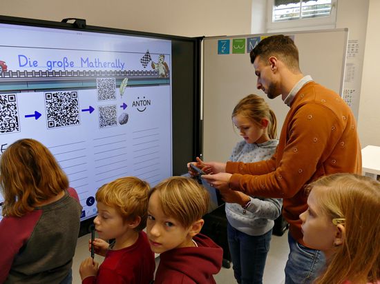 Kinder und ein Erwachsener an einem Whiteboard, auf dem QR-Codes zu sehen sind