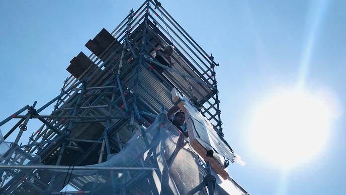 Auf der eingerüsteten Turmspitze der Stiftskirche Baden-Baden wird die Wetterfahne an einem Seil hochgezogen, um sie nach einer umfassenden Restaurierung wieder in über 60 Meter Höhe zu montieren.