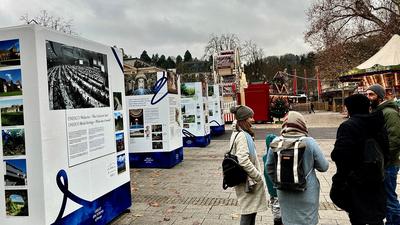 Eine Menschengruppe steht vor einer Reihe von Stelen, die über das Welterbe-Prädikat für Baden-Baden informieren.
