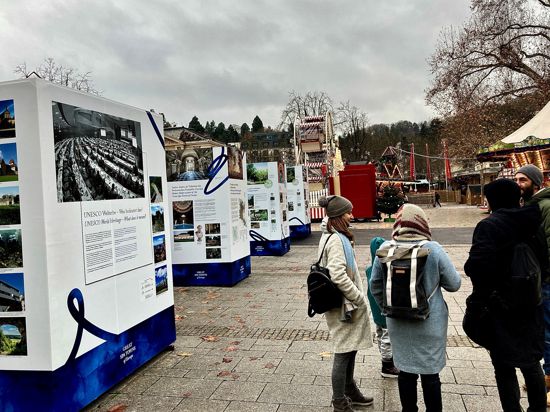 Eine Menschengruppe steht vor einer Reihe von Stelen, die über das Welterbe-Prädikat für Baden-Baden informieren.