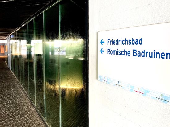 Ein Schild an einer Gebäudewand weist auf die Römischen Badruinen und das Friedrichsbad in Baden-Baden hin.
