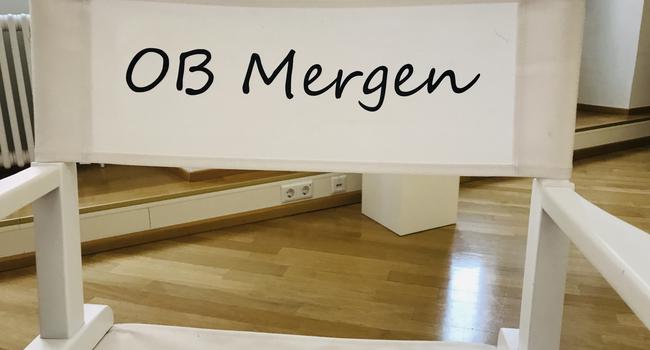 Ein Regiestuhl mit Aufschrift „OB Mergen“ steht an einem Tisch im Flur vor dem Büro von Oberbürgermeisterin Margret Mergen im Rathaus in Baden-Baden. 
