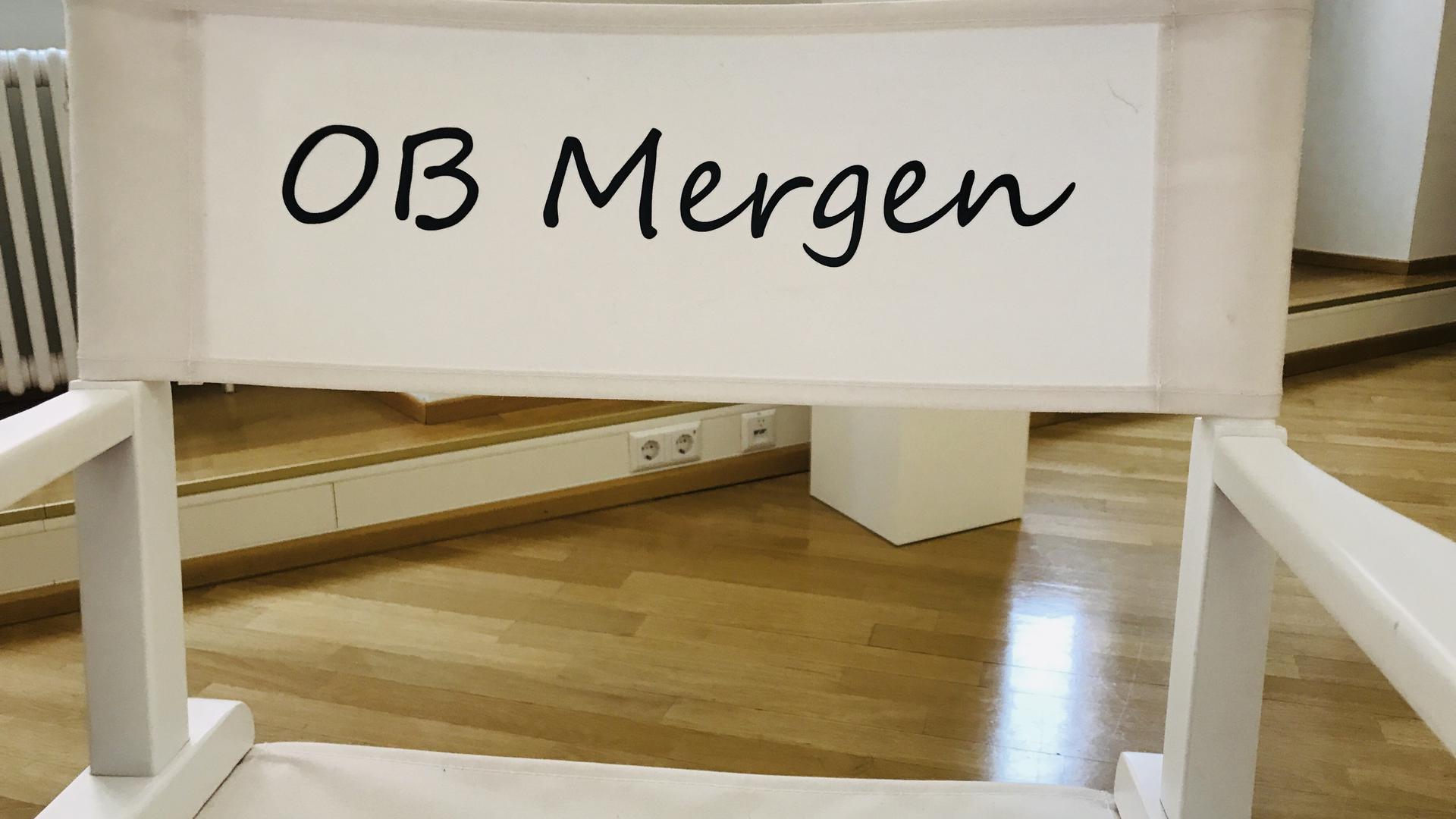 Ein Regiestuhl mit Aufschrift „OB Mergen“ steht an einem Tisch im Flur vor dem Büro von Oberbürgermeisterin Margret Mergen im Rathaus in Baden-Baden. 