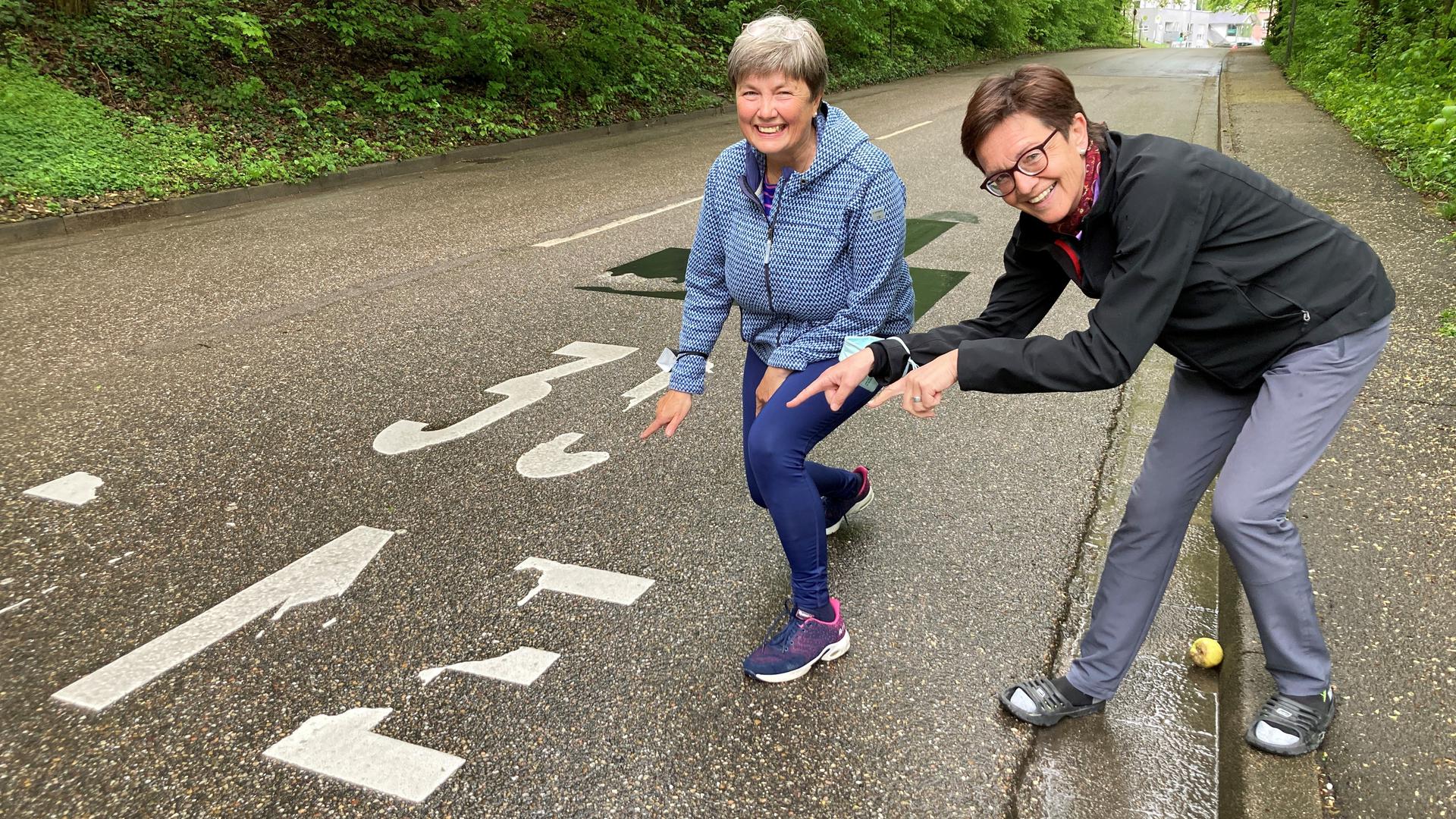 Zwei Frauen zeigen auf die kaum noch lesbare Markierung „30 Zone“ in der Rotenbachtalstraße hin.