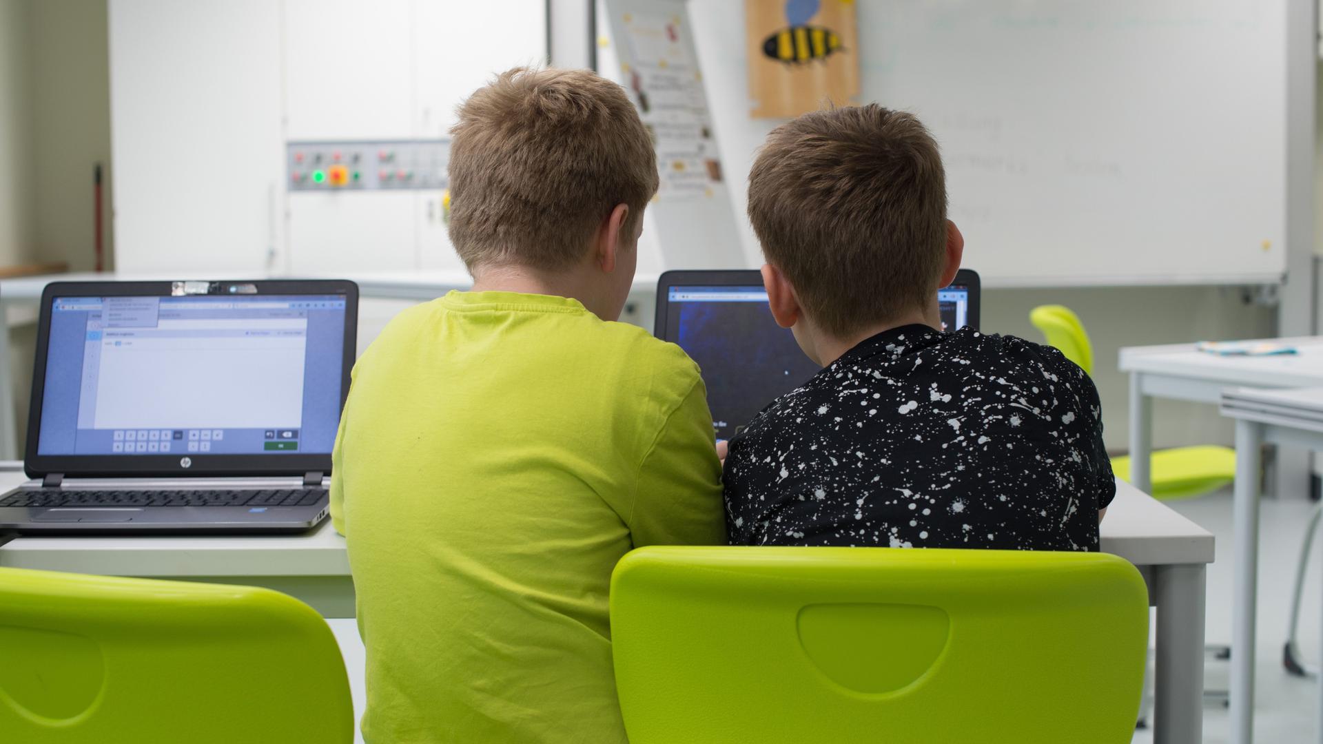 Zwei Schüler arbeiten einer Grundschule  an einem Laptop. 