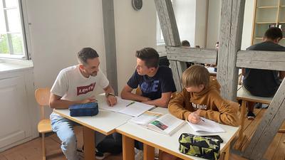 Betreut die Sommerschule: Lehrer Jan-Henrik Matthies tauscht sich mit Luca und Till, die gemeinsam Physik lernen, aus (von links).