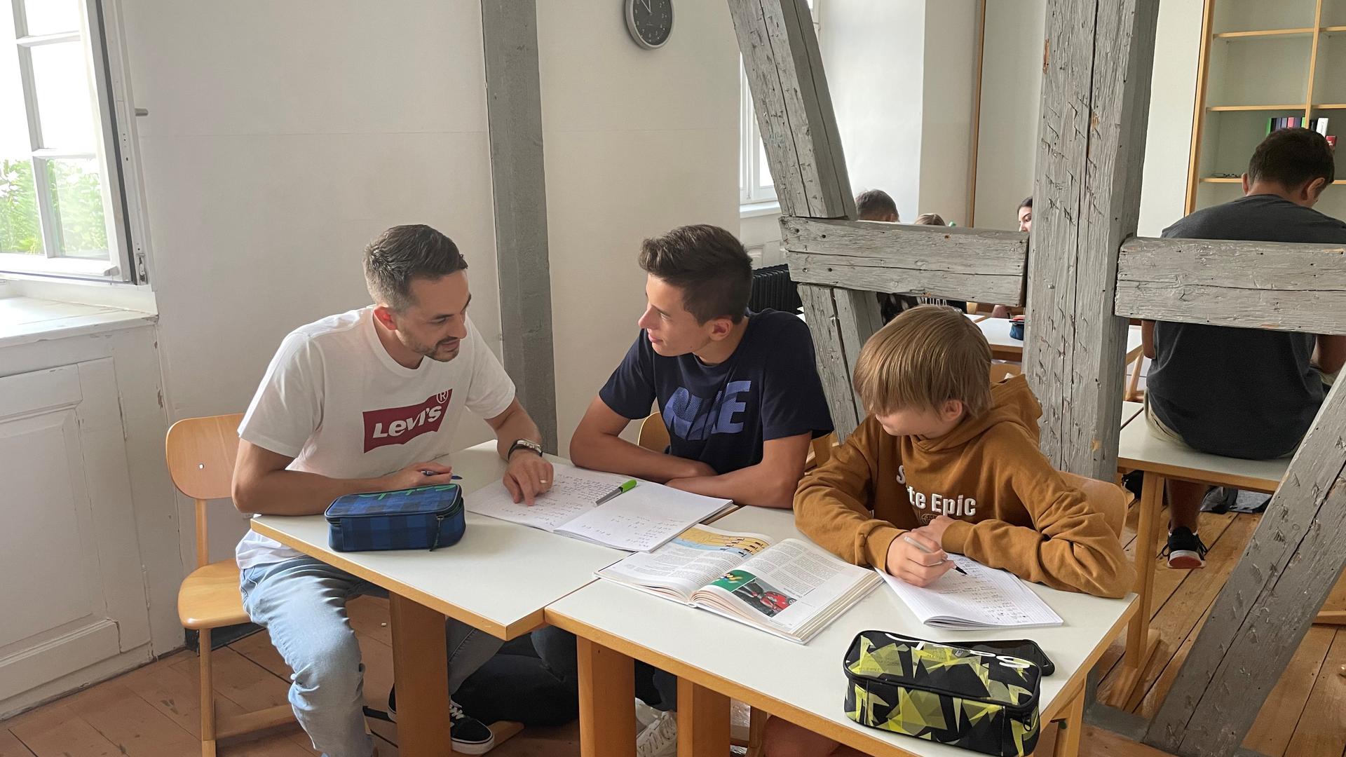 Betreut die Sommerschule: Lehrer Jan-Henrik Matthies tauscht sich mit Luca und Till, die gemeinsam Physik lernen, aus (von links).