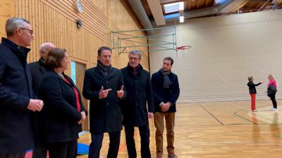 Kultusministerin Theresa Schopper steht mit einer Gruppe Menschen in der Sporthalle der Sportschule Steinbach.