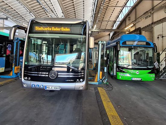 Zwei Busse stehen in einer großen Wagenhalle. 