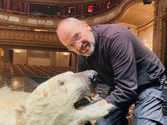 Schauspieler Oliver Jacobs zeigt auf der Bühne des Theaters in Baden-Baden das Eisbärenfell, über das er bei der Aufführung des Kult-Sketches „Dinner for One“ mehrfach stolpert. 