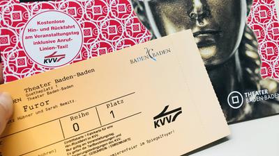 Eine Hand hält eine Eintrittskarte für das Theater Baden-Baden, die auch als Fahrkarte im öffentlichen Personennahverkehr gilt. 