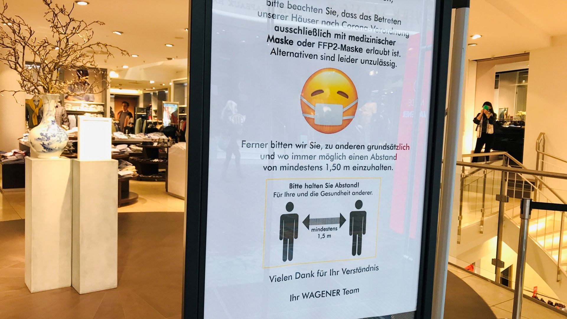 Maske ist Pflicht: Darauf weist eine Info-Tafel am Eingang des Kaufhauses Mode Wagener in der Fußgängerzone in Baden-Baden hin. 