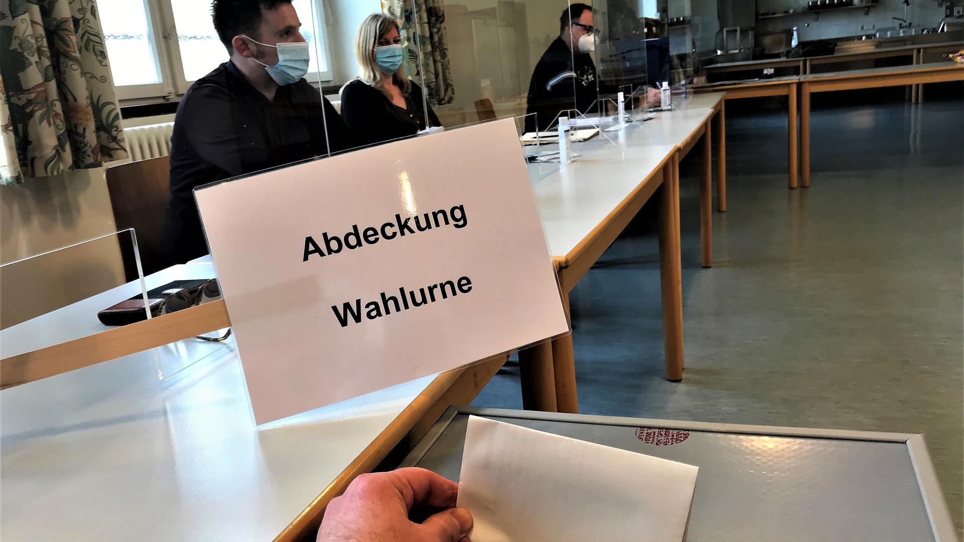 Wahlhelfer sitzen an einem Tisch im Wahllokal Werkrealschule Baden-Baden-Lichtental.