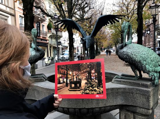 Ein Frau betrachtet den Welterbe-Adventskalender der Stadt Baden-Baden vor dem Reiherbrunnen in der Sophienstraße