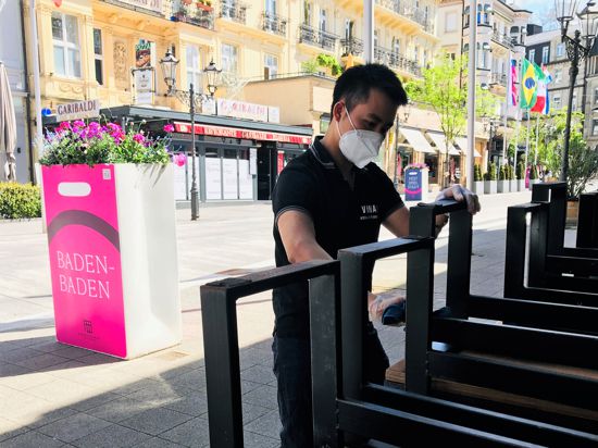 Ein Mitarbeiter eines vietnamesischen Restaurants in der Baden-Badener Innenstadt reinigt Möbel für die Bewirtung im Außenbereich. 